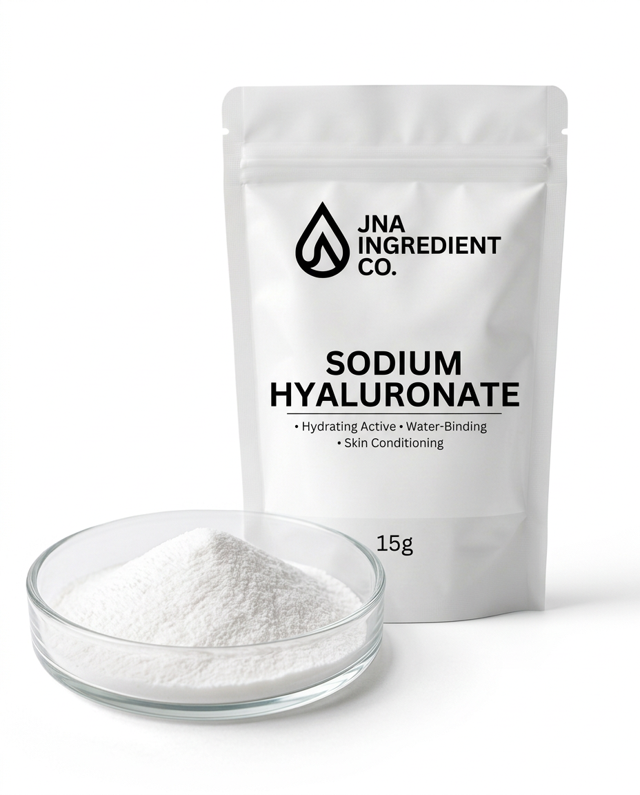 A white stand-up pouch labeled 'JNA INGREDIENT CO. SODIUM HYALURONATE' stands behind a small clear glass dish filled with white powder on a clean white background.